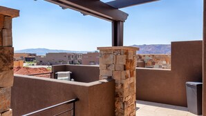 A rooftop terrace with stone walls, a pergola, and a view of distant buildings and mountains. - Your Escape at the Ledges (St. George)