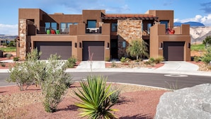 A modern two-story house with a garage, a balcony, and a landscaped front yard. - Your Escape at the Ledges (St. George)