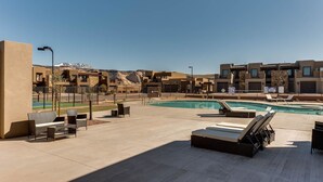 A rooftop pool area with lounge chairs, a pool, and modern buildings in the background. - The Perfect Place (St. George)