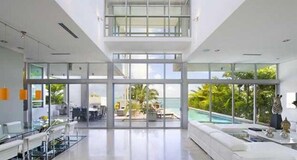 A spacious, modern hotel lobby with a large glass wall offering a view of an outdoor pool and lush greenery.