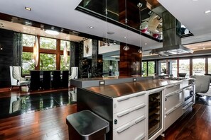 A modern kitchen with a large island, stainless steel appliances, and a view of the outdoors. - Villa Trystan (Miami Beach)