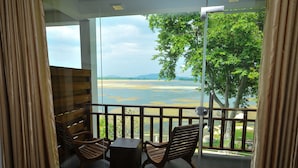 A balcony with wooden furniture and a view of a lake and mountains. - Peacock Wild Yala (Thissamaharama)