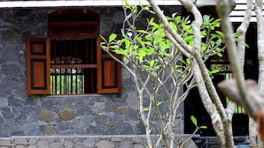 A stone building with a window featuring wooden shutters and a decorative wooden frame. - Peacock Wild Yala (Thissamaharama)
