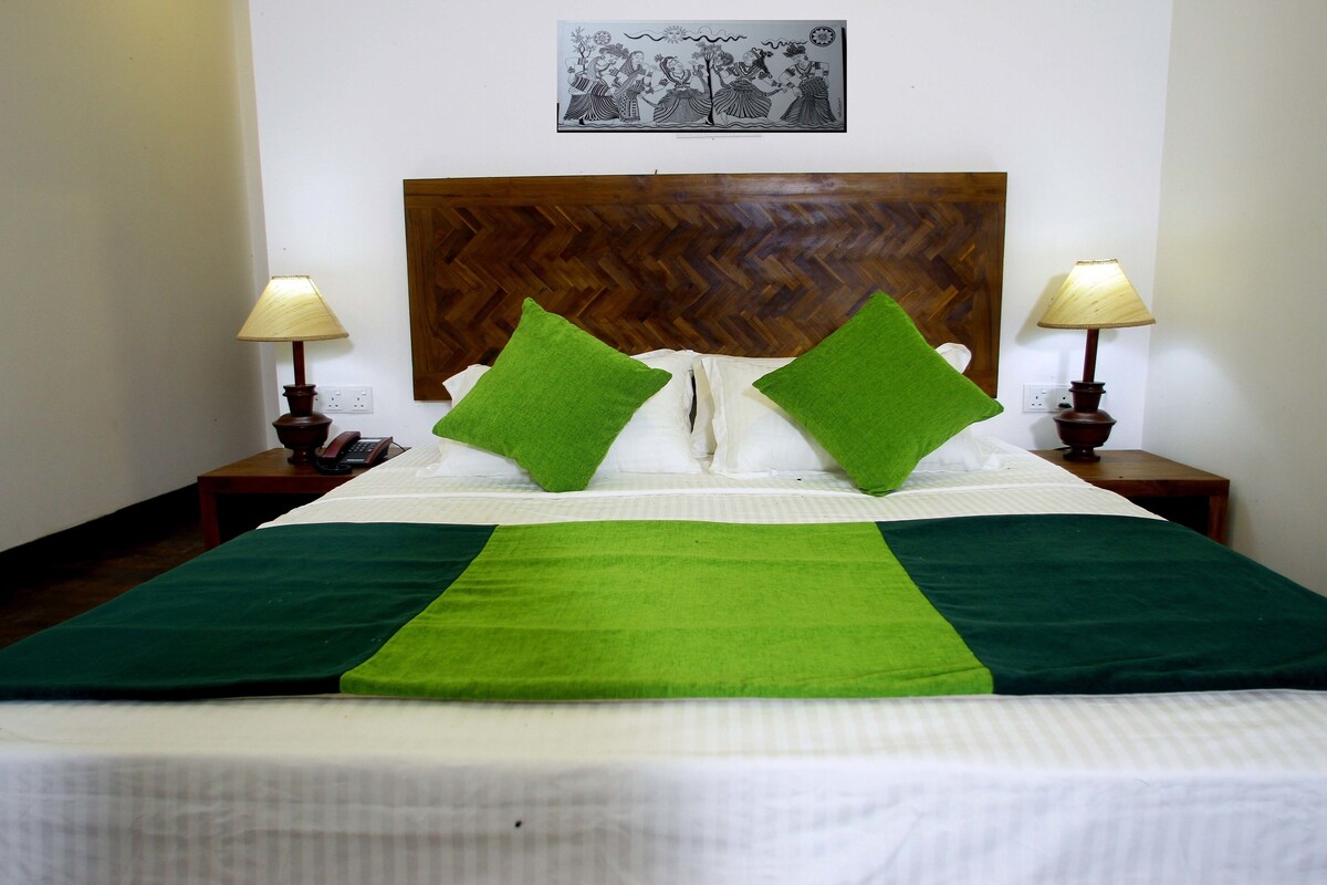 A neatly made bed with green pillows, a wooden headboard, and two bedside lamps.