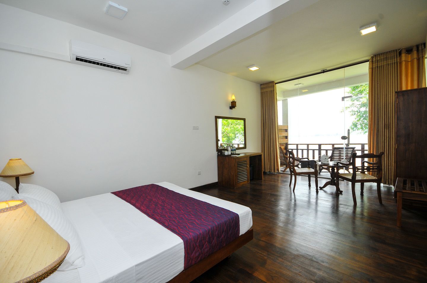 A hotel room with a bed, a desk, a chair, and a balcony with a view.