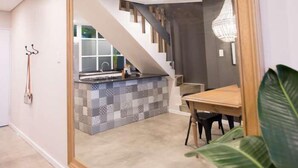 Una cocina moderna con salpicadero de cuadros, una mesa de comedor de madera y una escalera que sube a otro nivel.