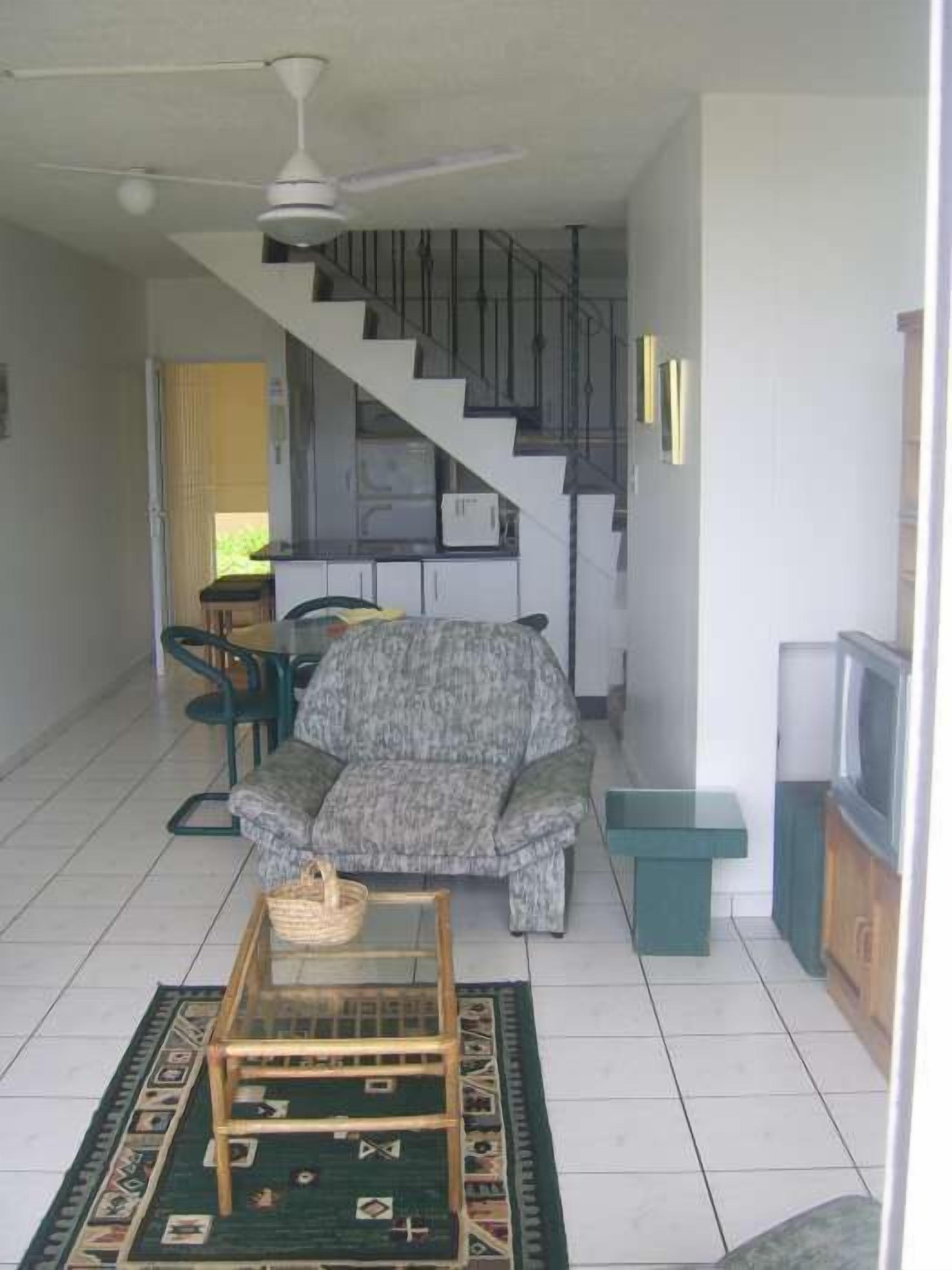 A living room with a sofa, a coffee table, and a staircase leading to another level.