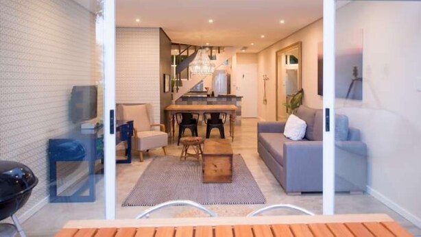 Un interior moderno con comedor, sofá y una escalera que conduce a otro nivel.