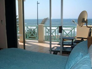 A bedroom with a view of the ocean, a balcony with a table and chairs, and a satellite dish. - Waterfront (eMdloti)