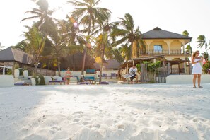 En la playa, arena blanca, sillas reclinables de playa, sombrillas