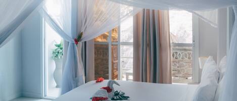 A neatly made bed with white linens, a bouquet of flowers, and a decorative towel arrangement.