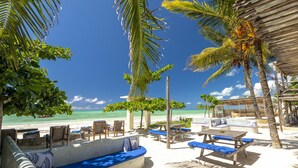 A beachside lounge with wooden furniture, a concrete bench, and a view of the ocean. - Paje Beach Apartments & Hotel (Paje)