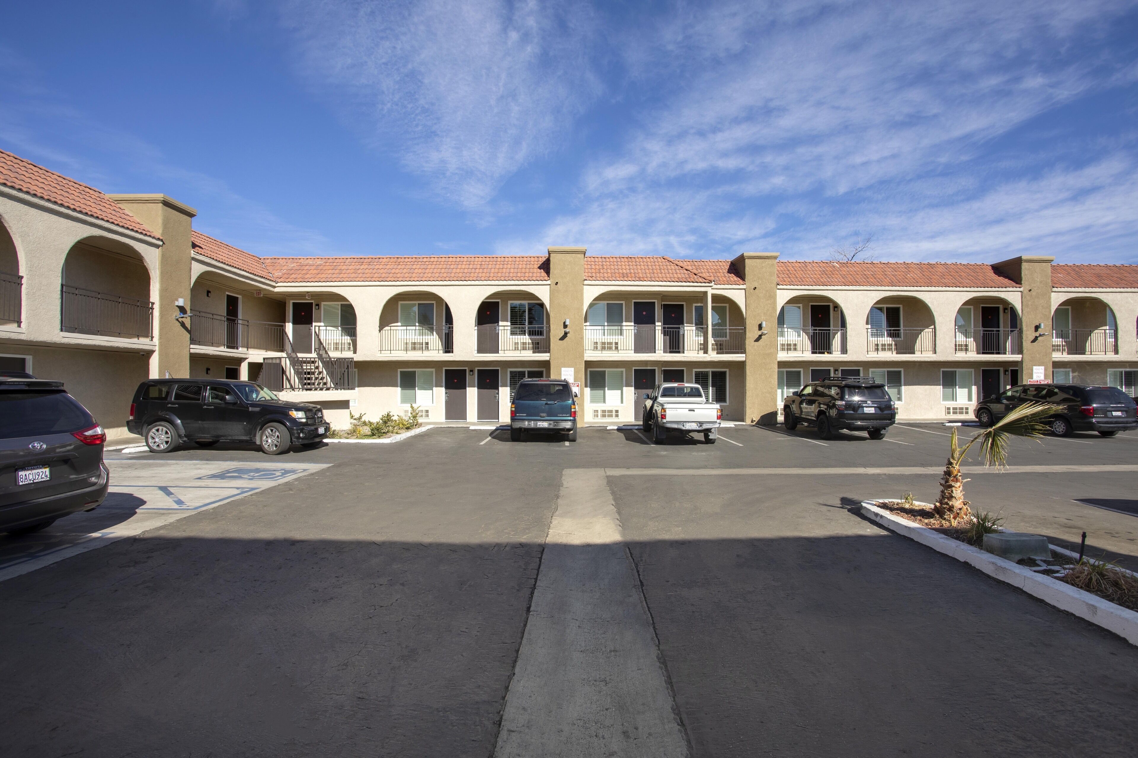 Motel de varios pisos con un patio central, que incluye un estacionamiento con varios vehículos.
