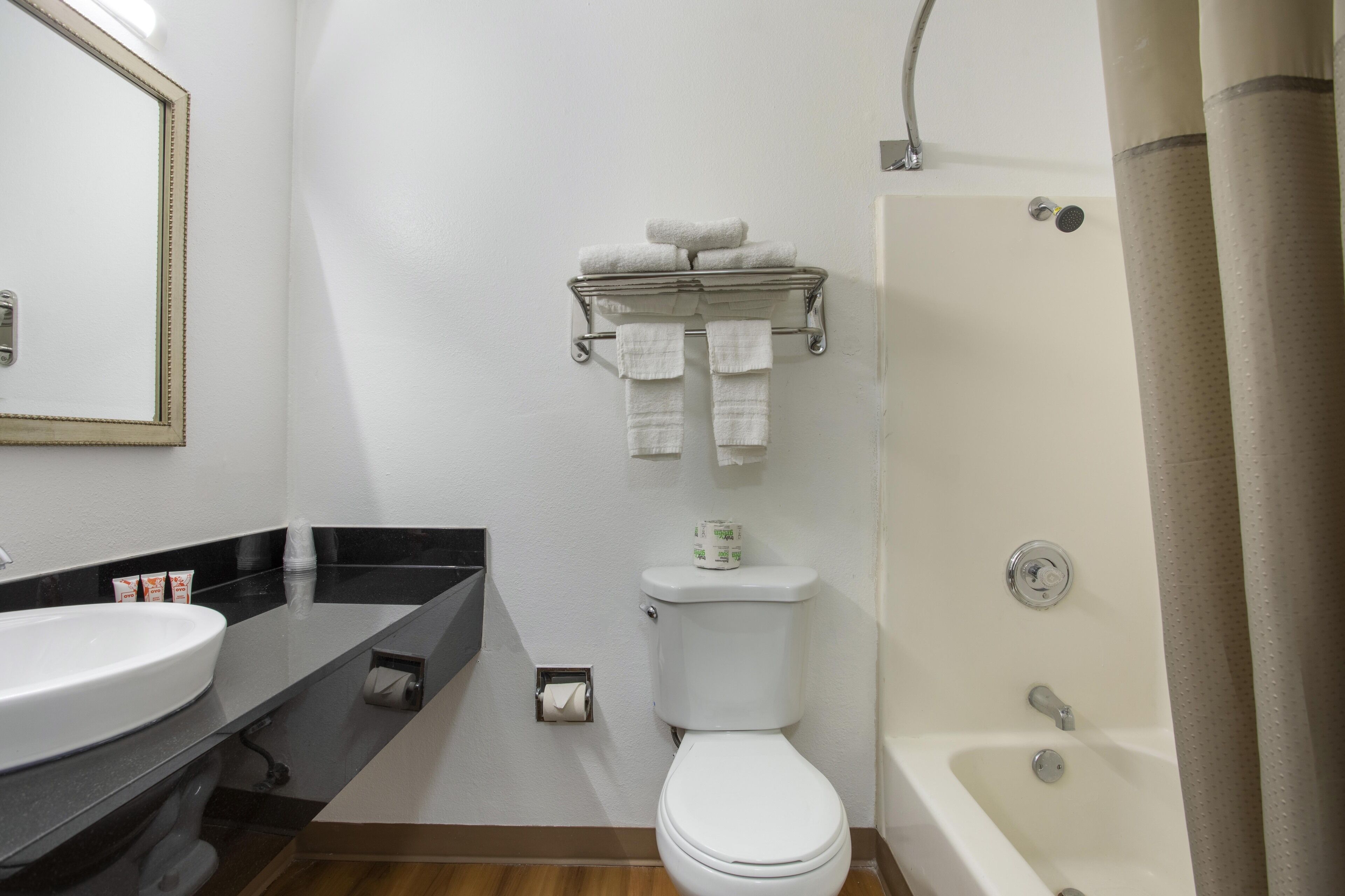 A bathroom with a white sink, toilet, and bathtub. There is a towel rack with folded towels above the toilet.