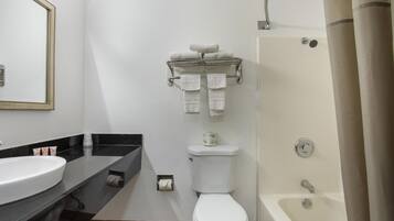 A bathroom with a white sink, toilet, and bathtub. There is a towel rack with folded towels above the toilet.