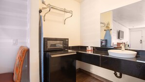 A modern bathroom with a black countertop, a white sink, and a microwave. - Hotel Palmdale - Antelope Valley (Palmdale)