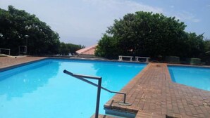 Una piscina rectangular con borde de ladrillo y escalera metálica.