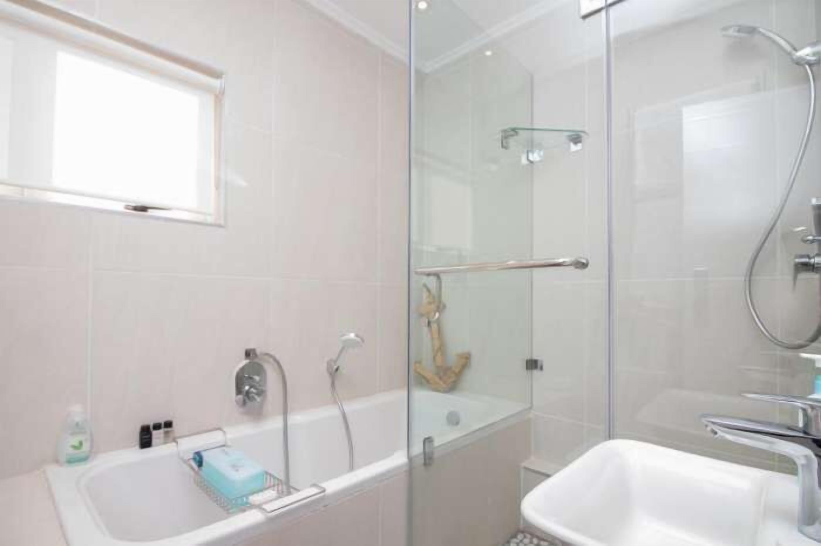 A modern bathroom with a glass-enclosed shower, a standalone bathtub, and a sink.