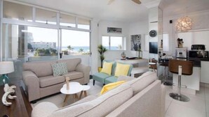 Una sala de estar moderna con sofá, mesa de centro y comedor con barra.