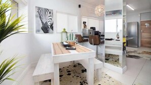 Una cocina moderna con armarios blancos, un comedor con mesa blanca y un cuadro de cebra en la pared.