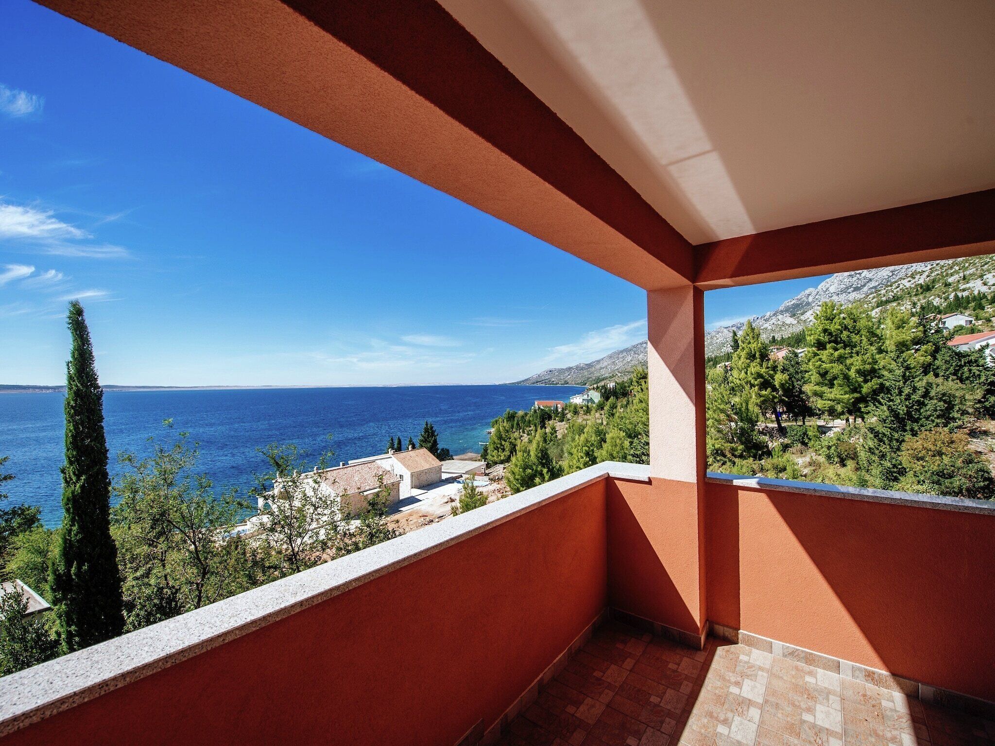 Un balcone con vista sul mare e sulla vegetazione circostante.