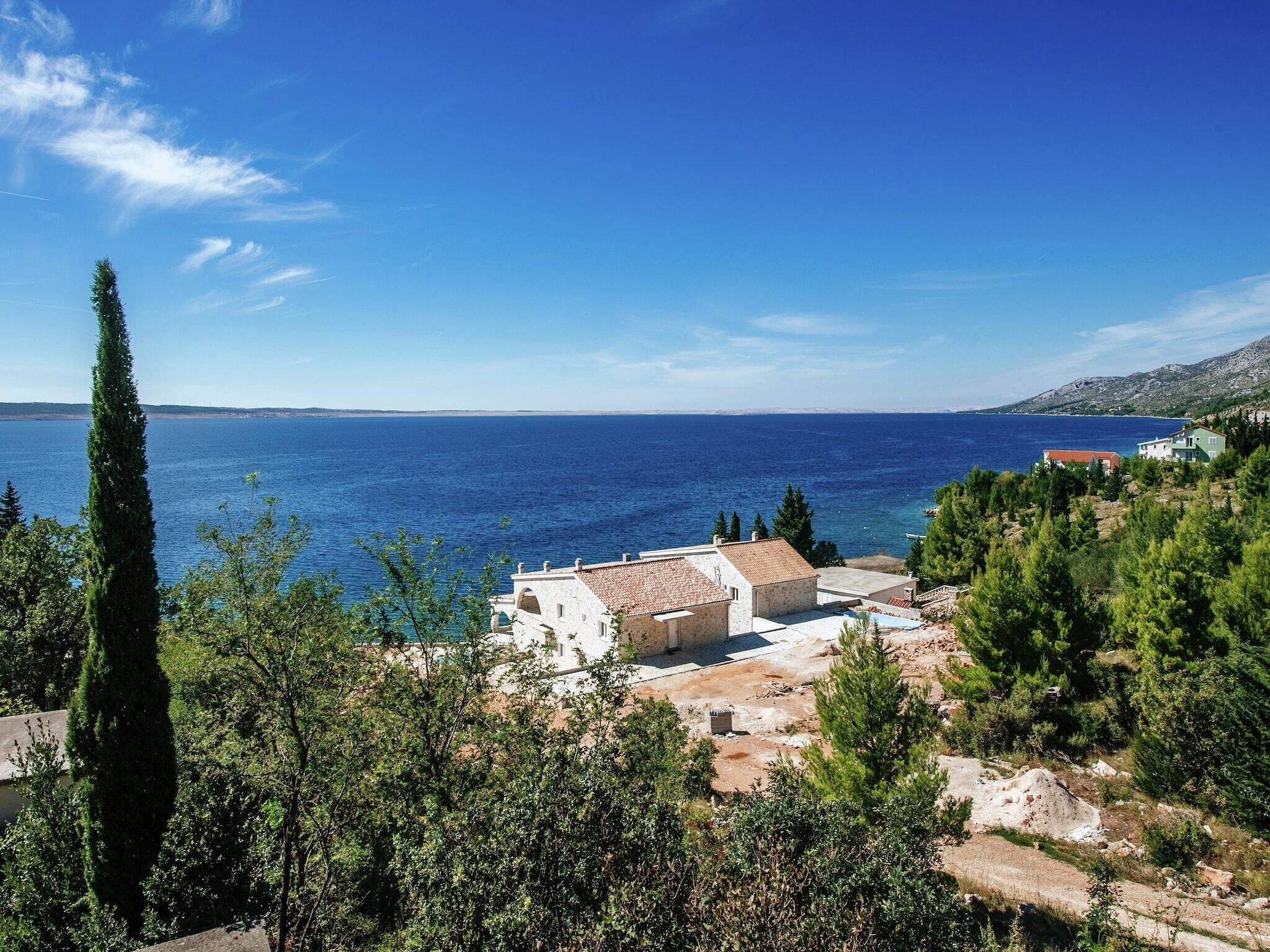 A coastal view with buildings, trees, and a clear blue sea.
