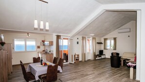 A spacious living area with a dining table, chairs, and a television. - Apartment in Starigrad near the Sea (Starigrad Paklenica)