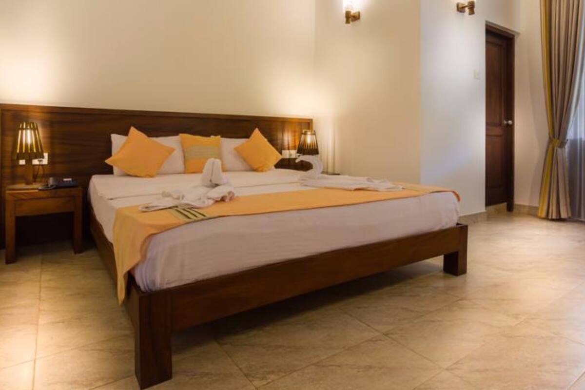A neatly made bed with a wooden headboard, a bedside table with a lamp, and a window with curtains.