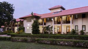 A multi-story hotel with balconies, a flat roof, and a well-maintained garden. - Chenra Hotel (Kataragama)