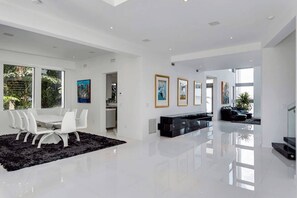 A spacious living area with a modern dining table and chairs, a black sofa, and artwork on the walls. - Villa Venetian Star (Miami Beach)