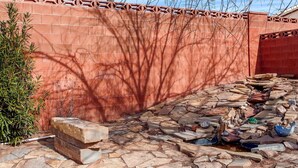 A construction site with a red brick wall, scattered stones, and a small pond with a fish sculpture. - Gateway to Zion (La Verkin)