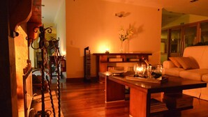 A cozy living room with a wooden coffee table, a sofa, and a bookshelf. - Alma Andina Hosteria (Villa La Angostura)