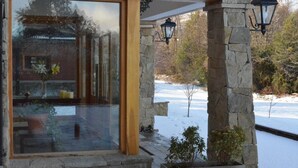 A modern building with large glass doors, stone pillars, and outdoor lighting. - Alma Andina Hosteria (Villa La Angostura)