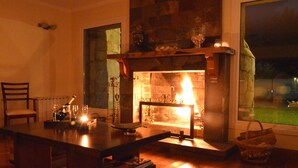 A cozy room with a fireplace, wooden furniture, and a view of the outdoors. - Alma Andina Hosteria (Villa La Angostura)