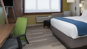 Una habitación de hotel con cama, escritorio, silla y ventana.
