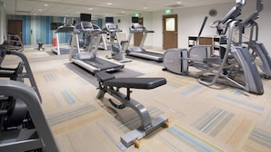 Une salle de sport équipée de tapis de course, de vélos elliptiques et de bancs de musculation.