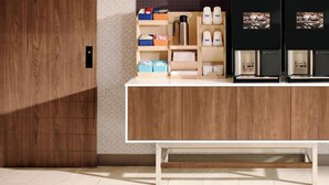 Una cocina moderna con armarios de madera, encimera blanca y una cafetera.