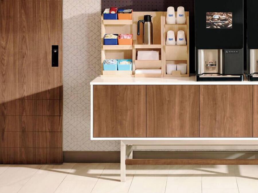 A modern kitchen with wooden cabinets, a white countertop, and a coffee machine.