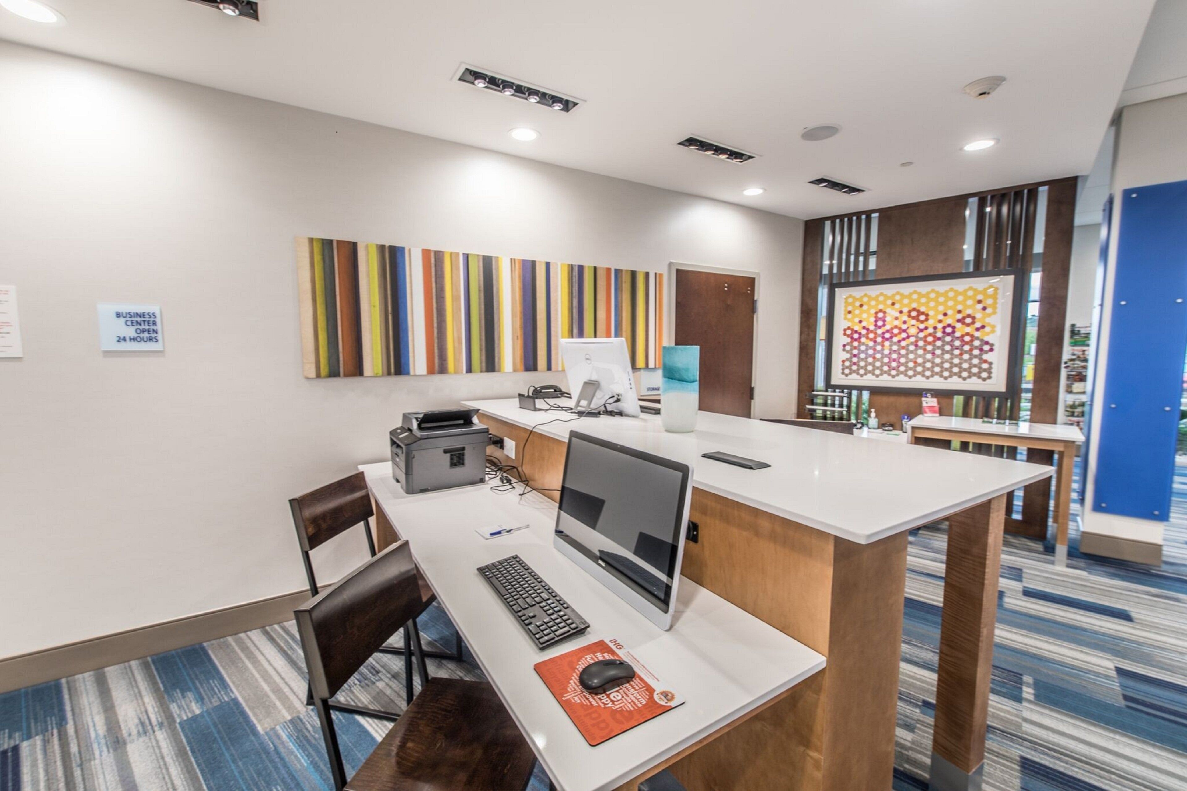 A modern business center with a desktop computer, printer, and a large window with a view.