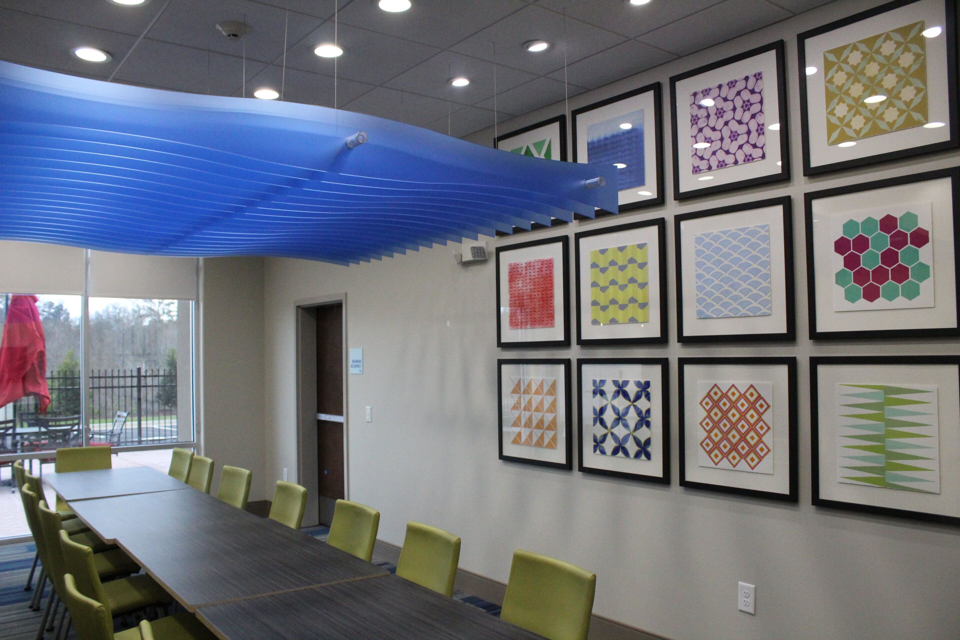 A conference room with a long table and chairs, framed artwork on the walls, and a blue ceiling feature.