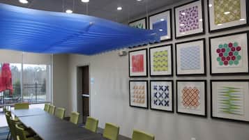 A conference room with a long table and chairs, framed artwork on the walls, and a blue ceiling feature.