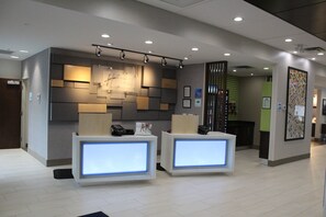 Zona de recepción con dos mostradores, un panel informativo en la pared y una escalera al fondo.
