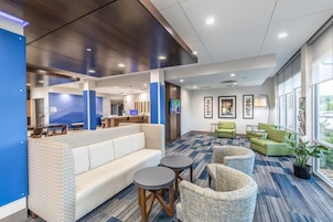 A modern lounge area with seating, a reception desk, and a large window providing a view.