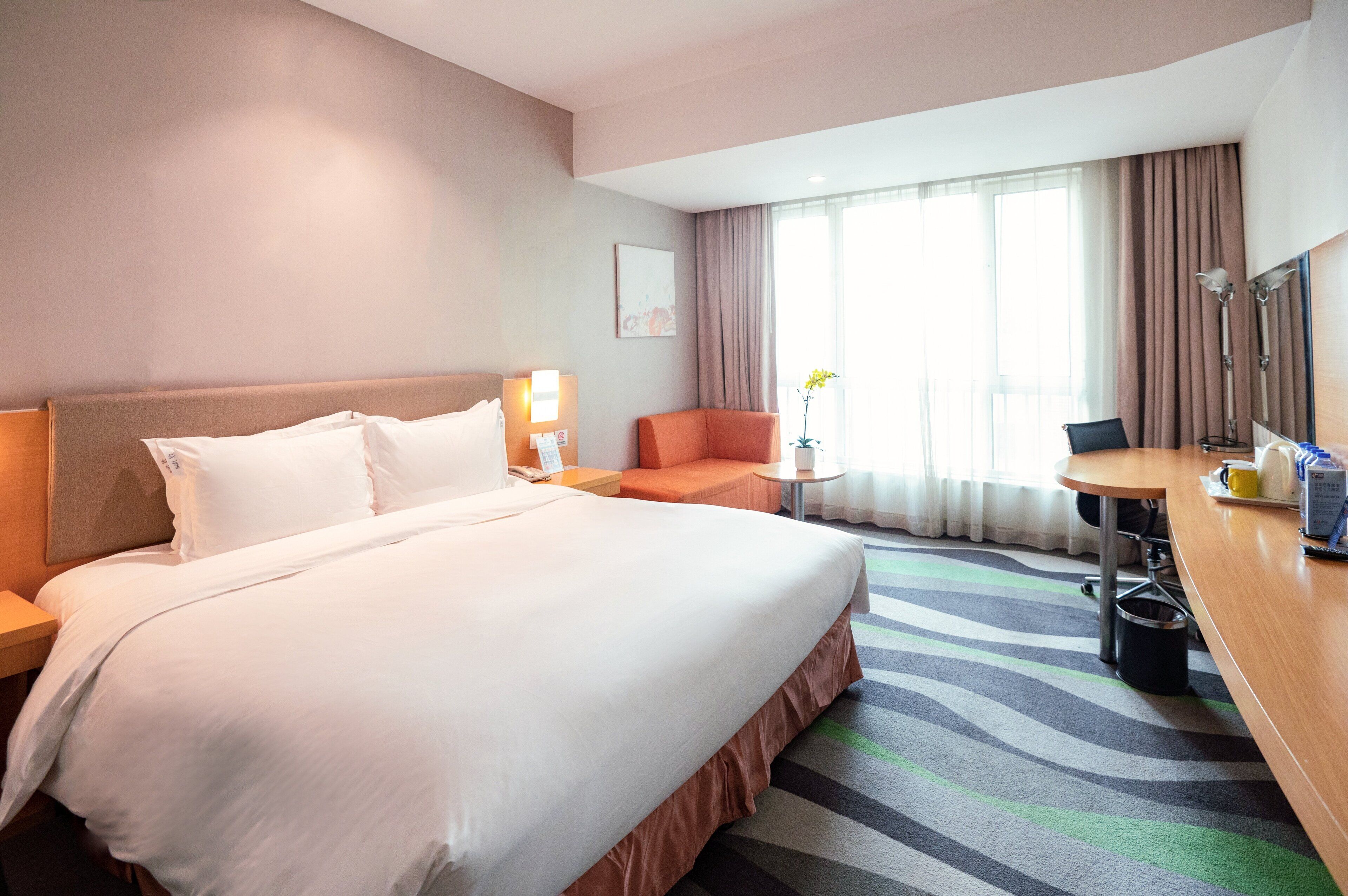 Une chambre d’hôtel avec un grand lit, un bureau, une chaise et une petite table.