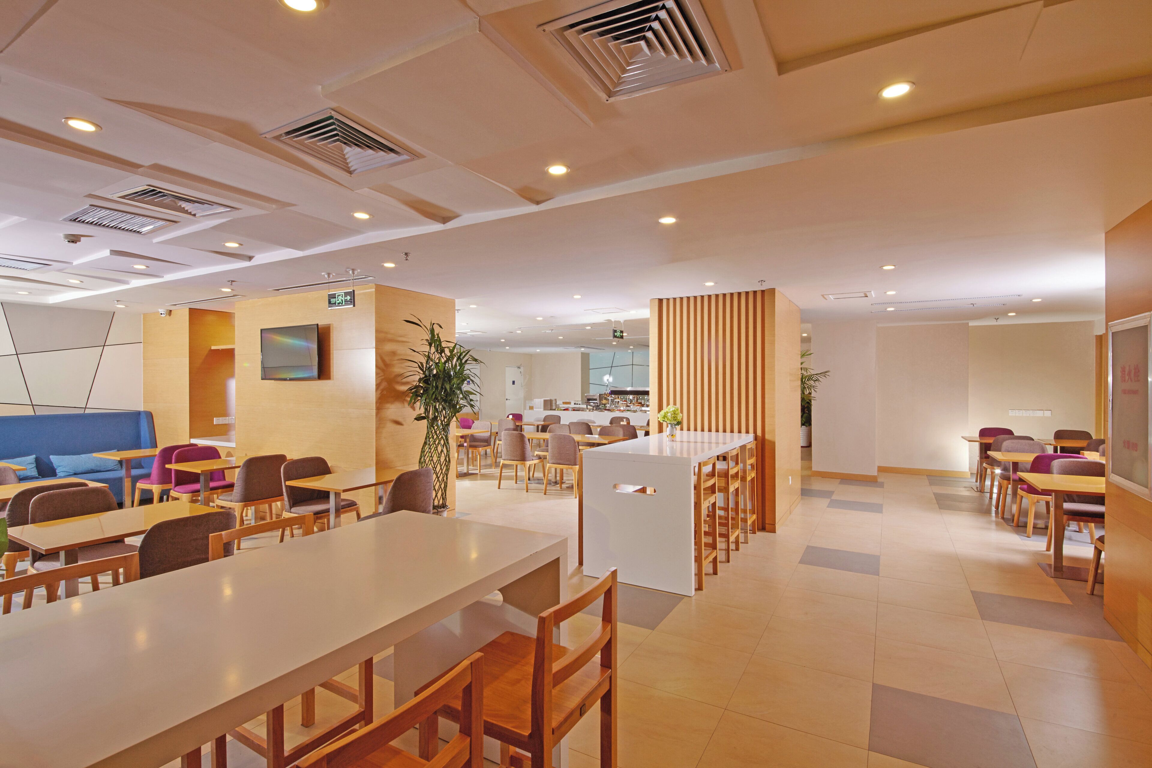 A modern dining area with tables and chairs, a blue sofa, and a plant.
