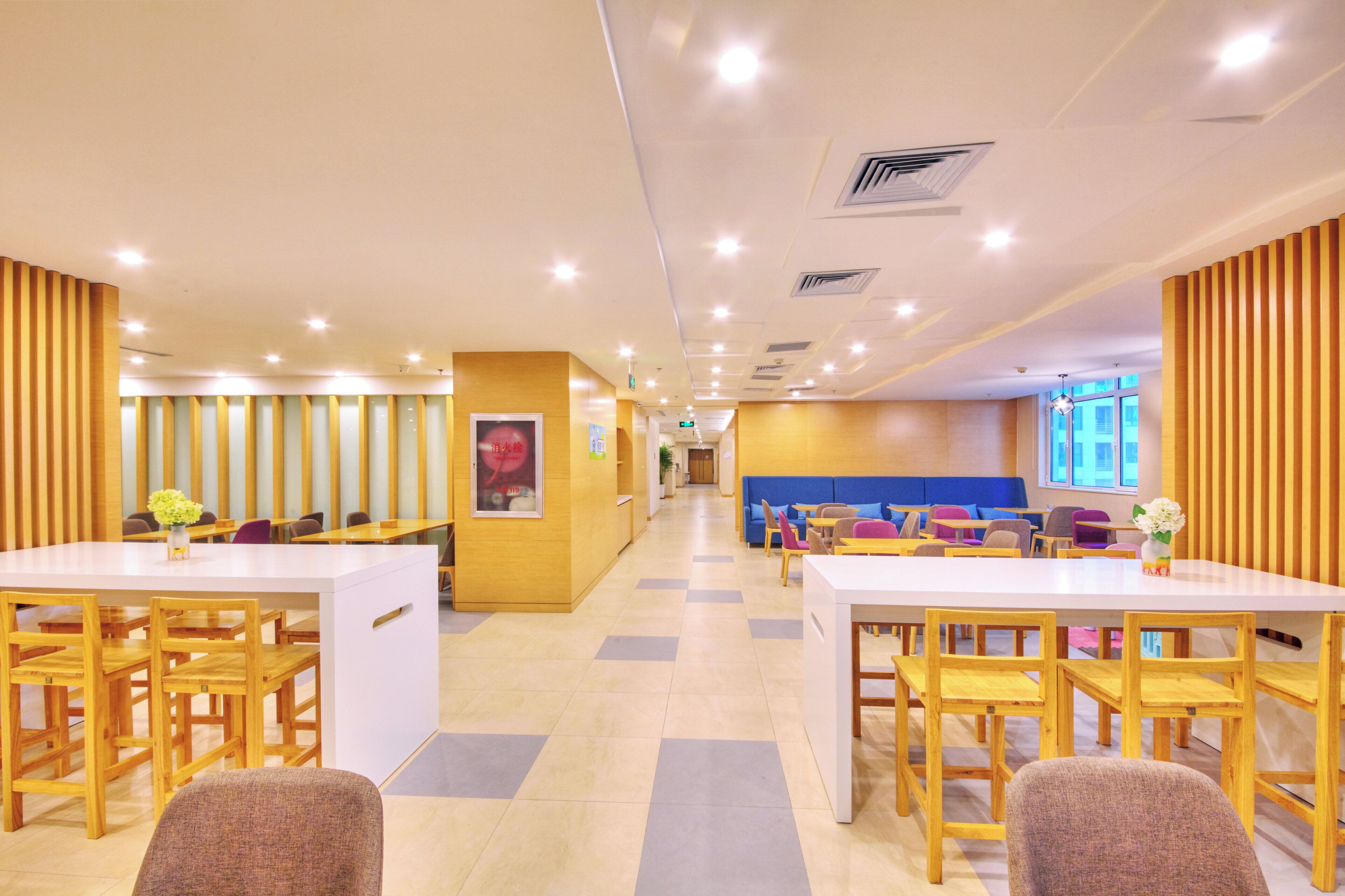 A modern interior with wooden panel walls, a central seating area with sofas and tables, and a bright, well-lit environment.
