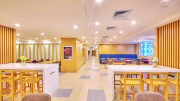 A modern interior with wooden panel walls, a central seating area with sofas and tables, and a bright, well-lit environment.