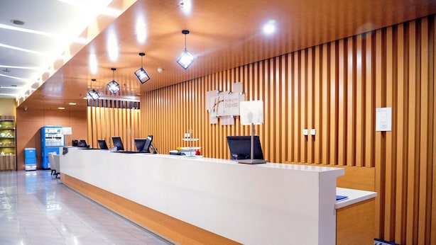 A reception area with a long white counter, wooden paneling on the walls, and a blue vending machine. - Holiday Inn Express Tangshan Downtown by IHG (Tangshan)