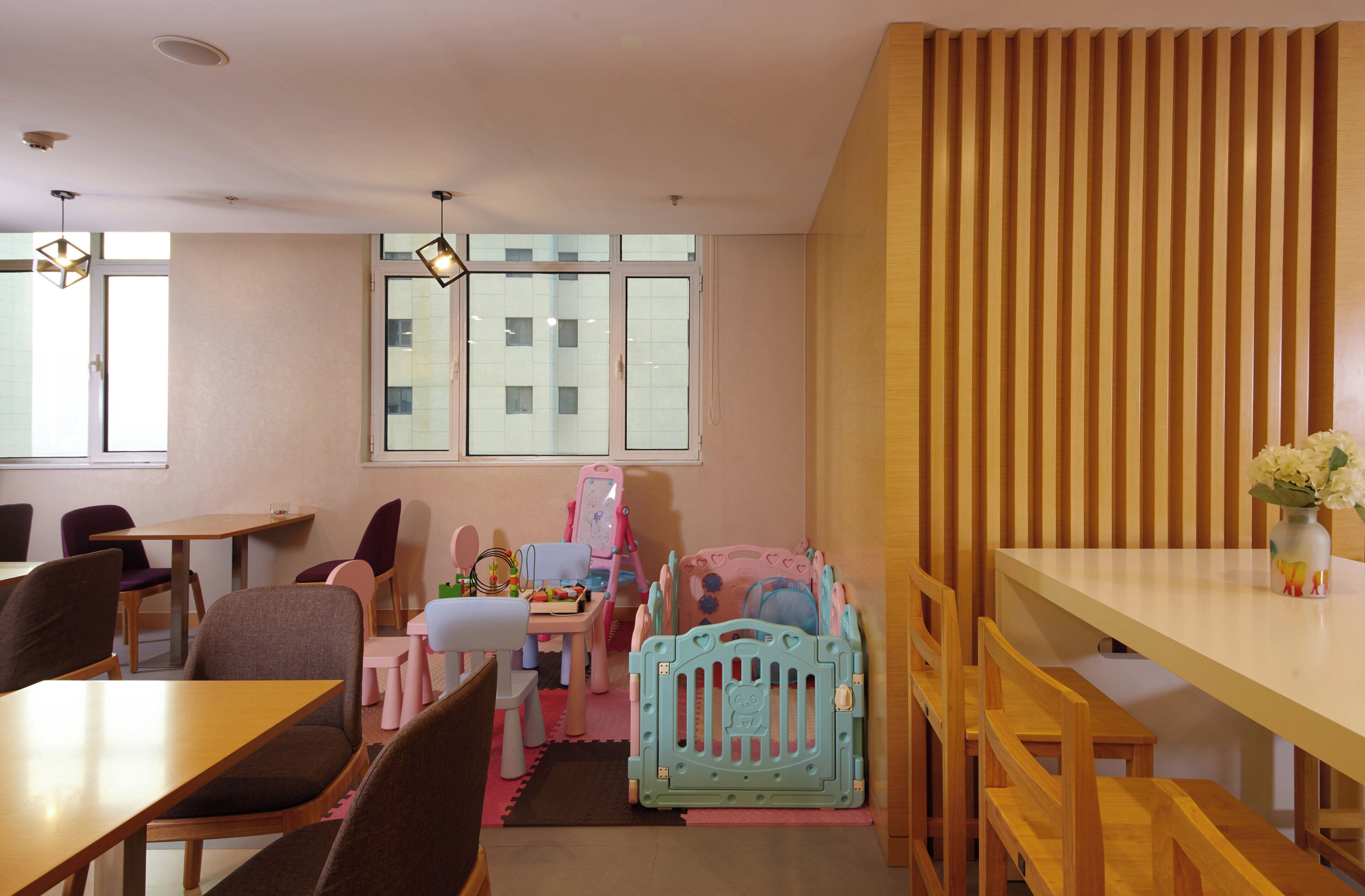 Un área de juegos infantiles con mesas, sillas y un corral.