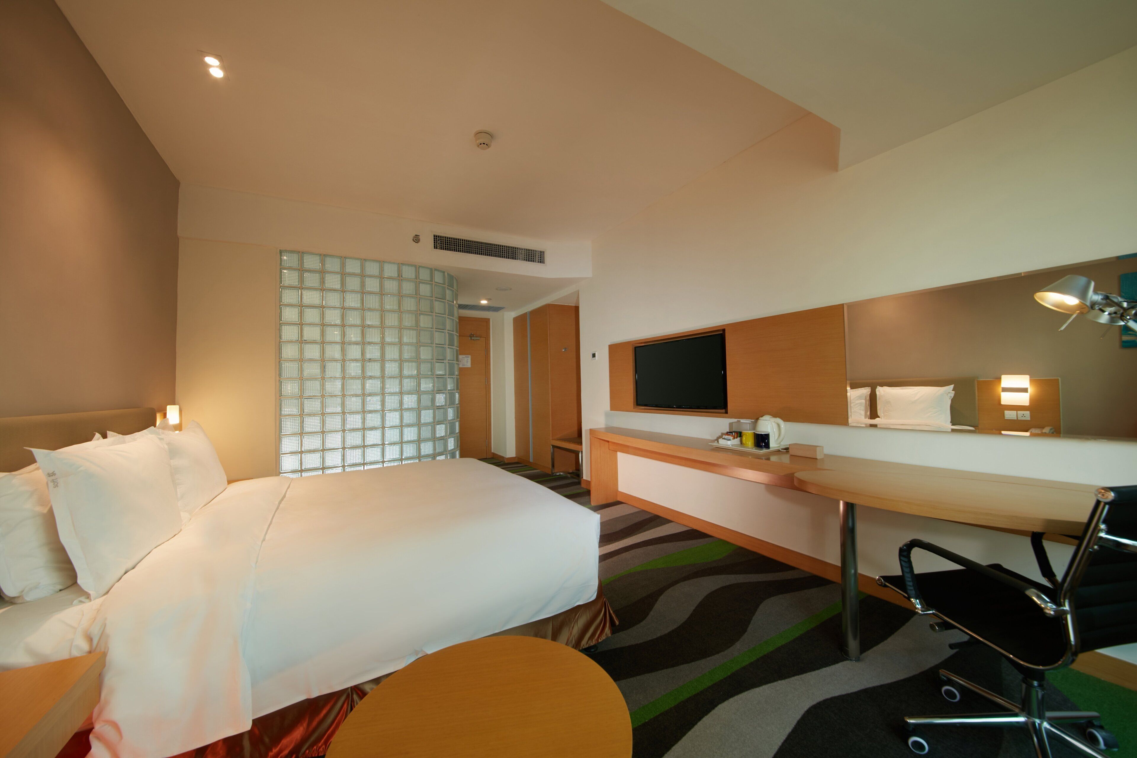 Een hotelkamer met een bed, bureau, stoel en televisie.